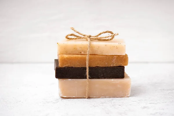 stock image Stack of natural soap bars tied with rope on light background