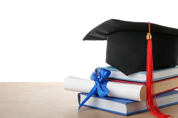 有文凭的毕业帽和白底书籍摆在桌面上 — 图库照片