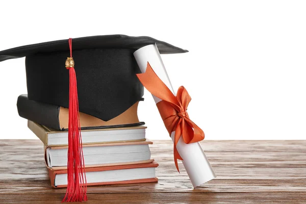 带毕业文凭的毕业帽和白色背景的木制桌子上的书 — 图库照片