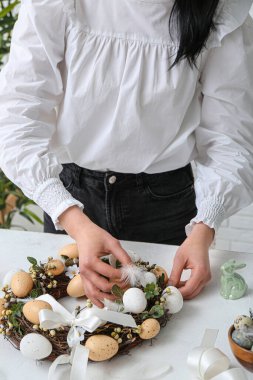 Beyaz masada Paskalya çelengi yapan kadın, yakın plan.