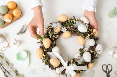 Beyaz masasında Paskalya çelengi olan bir kadın.