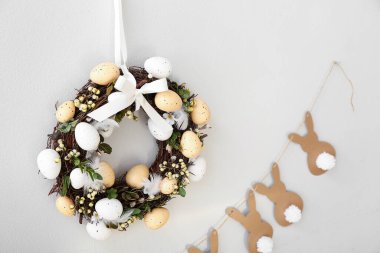 Paskalya çelengi ve kağıttan tavşanlar duvarda asılı, yakın plan.