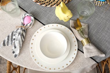 Tavşan kulaklarına sarılı Paskalya yumurtası peçete ve şenlik masasında tabaklar.