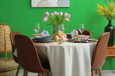 Paskalya kutlaması için masa üstünde lale çiçekleri olan güzel bir ortam. Renkli duvarın yanında.