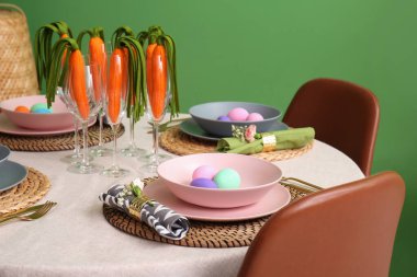 Renkli duvarın yanında dekoratif havuçlarla süslü Paskalya sofrası, yakın plan.