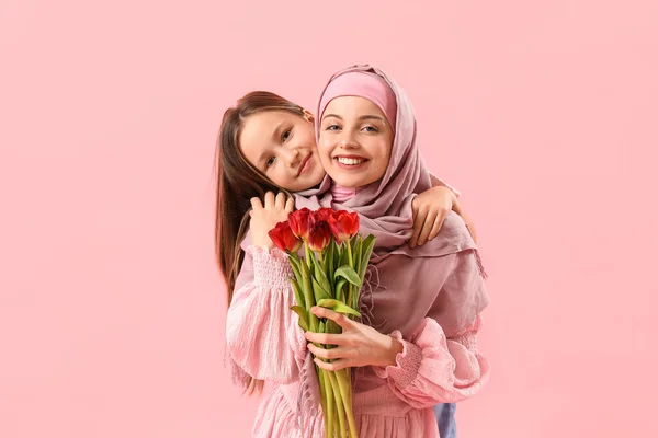 小さな女の子と彼女のイスラム教徒の母とともにチューリップ巨大上のピンクの背景 — ストック写真