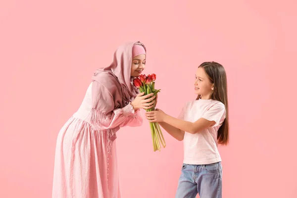 Kleines Mädchen Begrüßt Ihre Muslimische Mutter Mit Tulpen Auf Rosa — Stockfoto