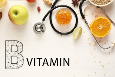 Sağlıklı ürünler, steteskop ve beyaz ahşap zemin üzerine VITAMIN B metni