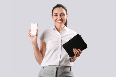 Gri arka planda not defterleri ve cep telefonu olan kadın iş danışmanı