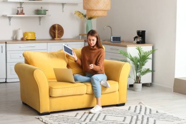 Güzel genç bir kadın dizüstü bilgisayarını taşınabilir güneş paneliyle şarj ediyor.