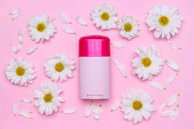 Kozmetik ürünlü kompozisyon ve pembe arka planda güzel papatya çiçekleri.