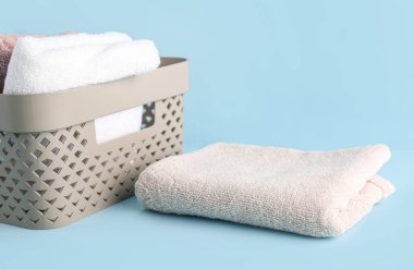 Mavi zemin üzerinde katlanmış yumuşak havlular olan sepet.