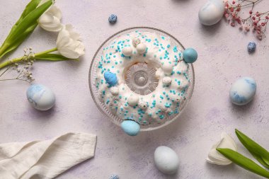 Composition with sweet Easter cake, flowers and eggs on light background