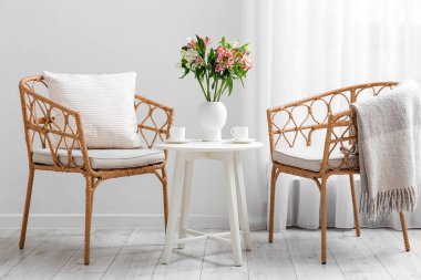 İçinde güzel alstromerya çiçekleri olan bir masa, oturma odasının içinde bir fincan kahve ve sandalyeler.