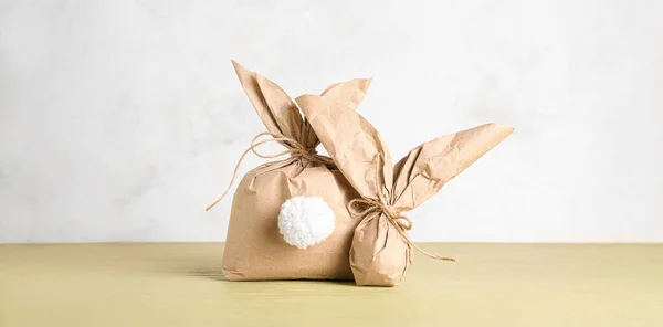 stock image Easter bunny gift bags on table against light background