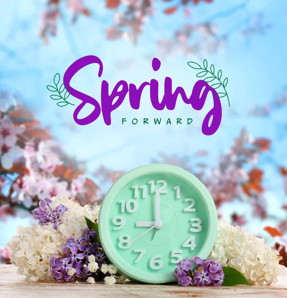 庭のテーブルの上の目覚まし時計とライラックの花 春の時間 — ストック写真