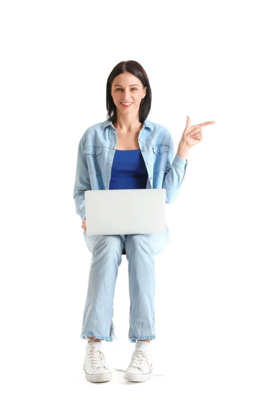 漂亮的年轻女人 拿着笔记本电脑 靠着白色的背景坐在椅子上 指着什么东西 — 图库照片