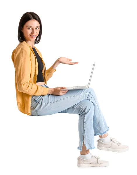 一个年轻漂亮的女人 拿着笔记本电脑坐在椅子上 背对着白色的背景 — 图库照片