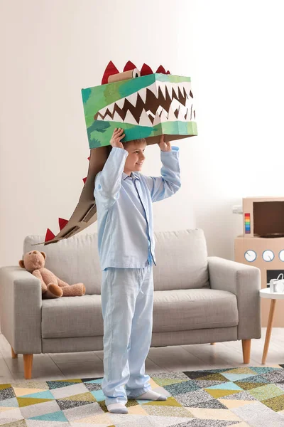 Little boy with cardboard dinosaur costume at home