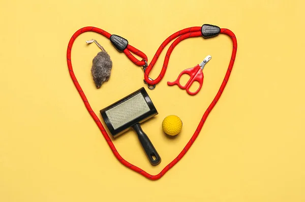 Heart made of pet care accessories on yellow background