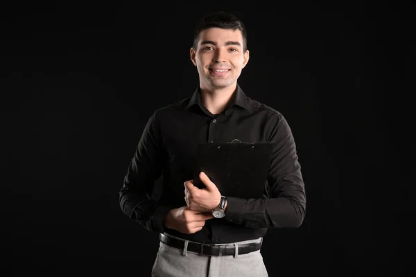 Business consultant with clipboard on dark background