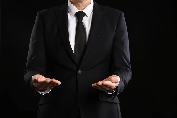 Mature business consultant showing hands on dark background, closeup