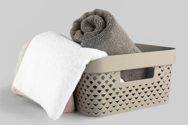 Basket with cotton soft towels on grey background