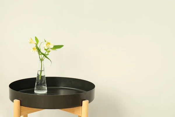 光の壁の近くのテーブルの上にアルストロメリアの花の枝を持つ花瓶 — ストック写真