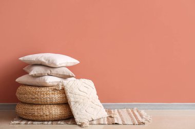 Pembe duvarın yanındaki hasır puflarda şık dekoratif yastıklar.