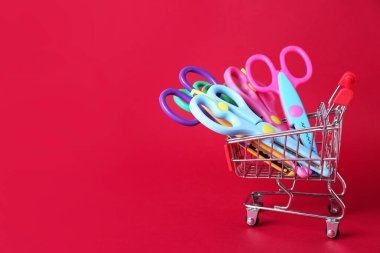 Renkli arka planda farklı makaslı alışveriş arabası