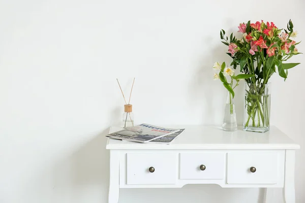 美しい星の花の花瓶 雑誌やライトウォールの近くのテーブルのリードディフューザー — ストック写真