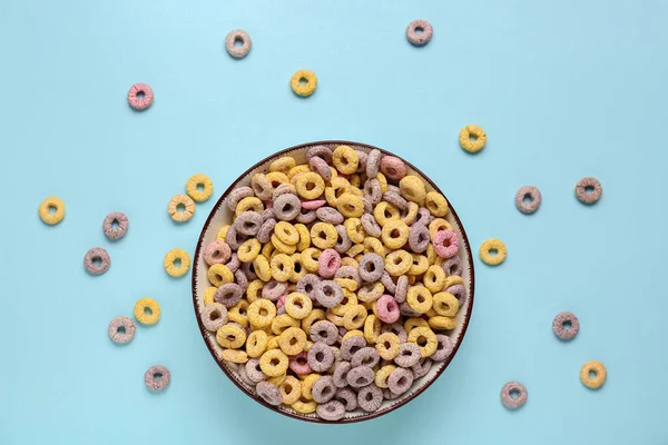 Bowl of colorful cereal rings on blue background
