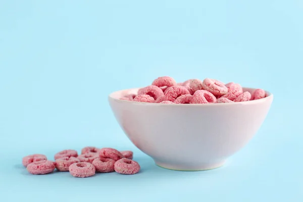 Bowl of pink cereal rings on blue background