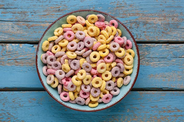 Bowl of colorful cereal rings on blue wooden background