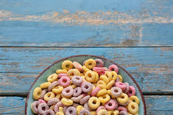 Bowl of colorful cereal rings on blue wooden background