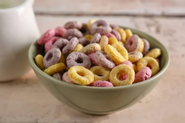 Bowl of colorful cereal rings on white wooden table, closeup