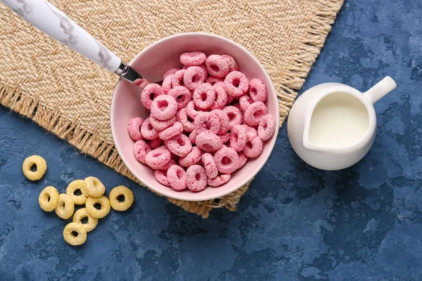 粉红麦片环和加牛奶的水壶 背景为蓝色 — 图库照片