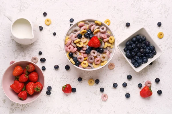 Bowl of colorful cereal rings with milk and berries on white grunge background