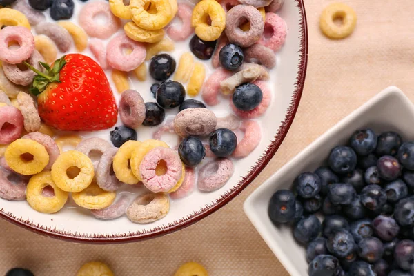 Bowl of colorful cereal rings with milk and berries on napkin