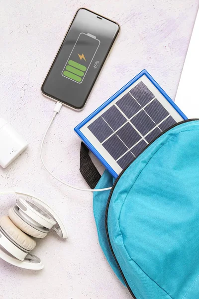 stock image Composition with portable solar panel charging mobile phone on white grunge background