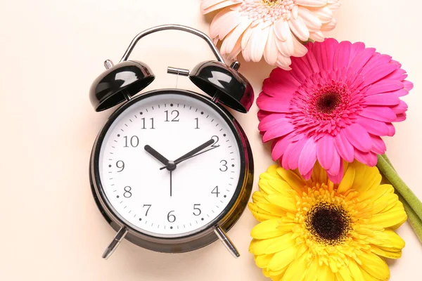 Väckarklocka Och Vackra Gerbera Blommor Beige Bakgrund — Stockfoto