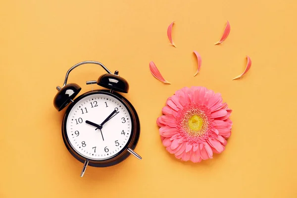 Σύνθεση Ξυπνητήρι Πέταλα Και Όμορφο Λουλούδι Ζέρμπερα Πορτοκαλί Φόντο — Φωτογραφία Αρχείου