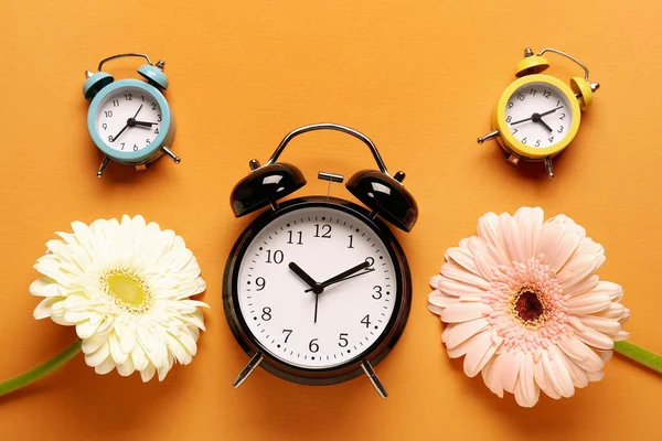 Relógios Alarme Belas Flores Gerbera Fundo Laranja — Fotografia de Stock