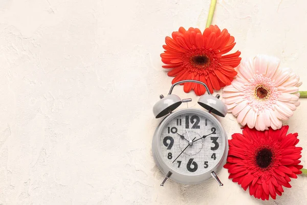 目覚まし時計と白いグランジの背景に美しいガーベラの花 — ストック写真