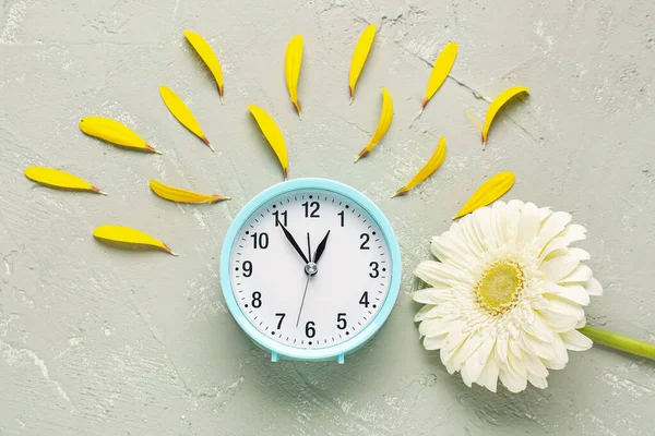 目覚まし時計 花弁とグレーのグランジの背景に美しいガーベラの花と組成 — ストック写真