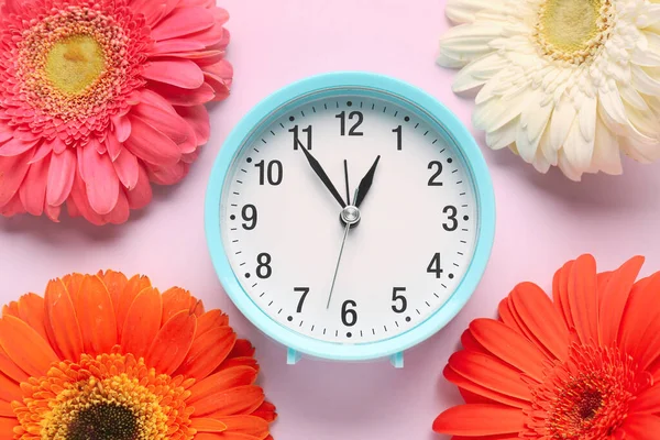 目覚まし時計とピンクの背景に美しいガーベラの花と組成 — ストック写真