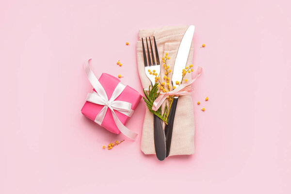 Комплект столовых приборов с цветами мимозы в салфетке и подарочной коробке на розовом фоне