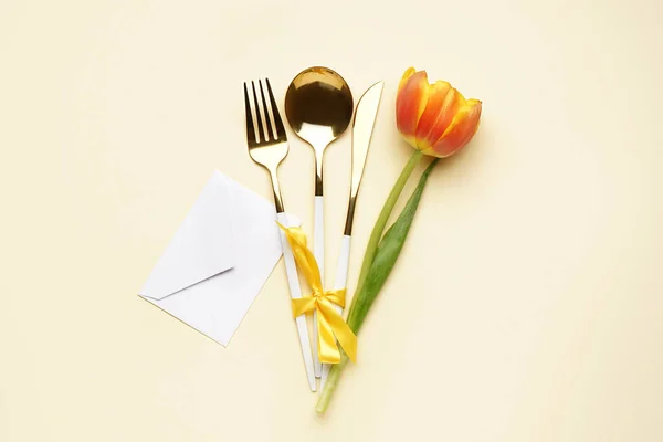 stock image Set of cutlery, beautiful tulip flower and envelope on beige background