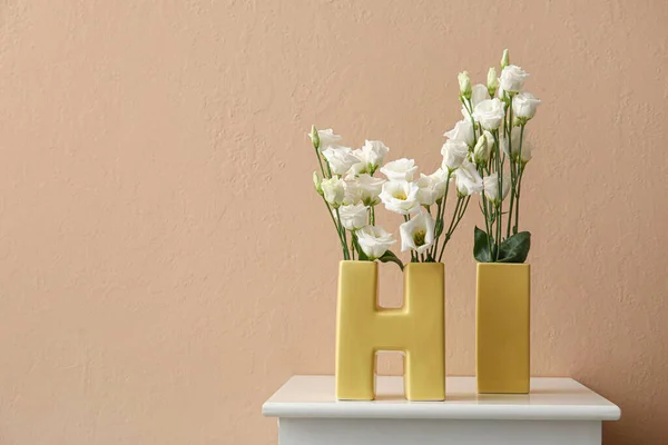 Wazony Kształcie Słowa Pięknymi Kwiatami Eustoma Stole Pobliżu Ściany Koloru — Zdjęcie stockowe