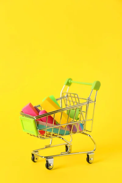 黄色の背景に消しゴムとチョークでショッピングカート — ストック写真